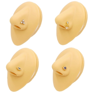 Lot de quatre piercings de nez dorés avec pendentif cœur et zircon sur modèle de nez