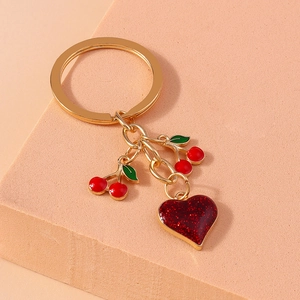 Elegant gold keychain with red enamel cherries and a glittery heart charm for handbags
