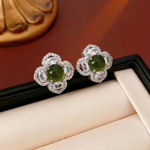 Macro view of flower stud earring with green gemstone and cubic zirconia in a jewelry box