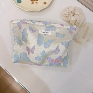 Detailed close-up of butterfly jacquard fabric and 'simple wish' tag on canvas makeup bag