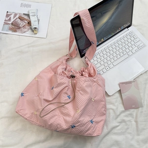 Vista dall'alto di borsa shopper a quadretti rosa con fiocchi ricamati e un laptop
