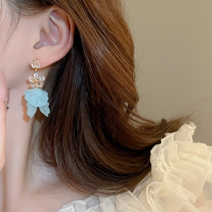 Détail de boucles d'oreilles fleuries vert menthe avec strass portées avec lumière douce