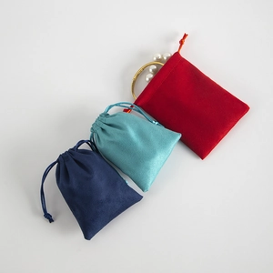 Close-up of colorful velvet drawstring pouches with a gold bracelet inside