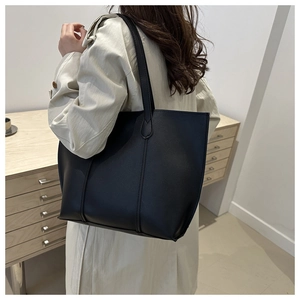 Detail view of large black leather tote bag with pebble texture and sturdy shoulder straps