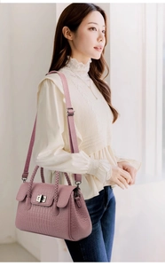 Detail of pink-purple crocodile pattern leather handbag with woven handles and silver lock