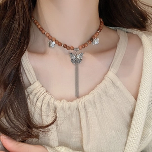 Détail du collier rétro en perles de santal avec gland papillon argenté sur un mannequin