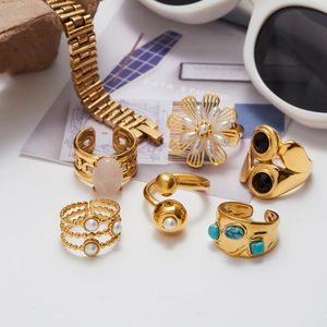 Collection of gold rings with turquoise and pearls on white desk lifestyle setting