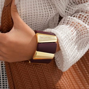 Detail of chunky acrylic geometric bracelet with gold metal links and purple resin
