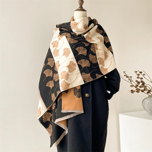 Close-up of thick cashmere scarf featuring elegant ginkgo leaf patterns and soft fringe trim