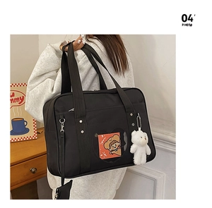 Detail of black JK school bag featuring a heart-shaped transparent window and plush bear charm