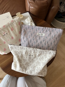 Detailed texture of cotton makeup bags with floral prints on a rustic wooden table