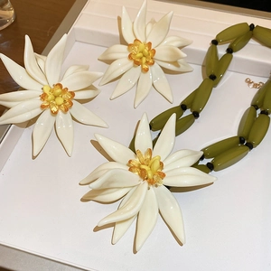 Detailed view of white floral necklace and earrings set in a white jewelry box