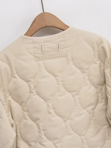 Macro detail of beige quilted jacket featuring intricate gourd pattern stitching