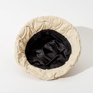 Chic beige quilted bucket hat with wavy stitching and contrast black lining for winter