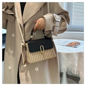 Detail of straw woven handbag with black leather flap and gold metal buckle close-up