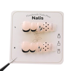 Handmade press-on nails featuring black French tips, polka dots, and glitter rhinestones