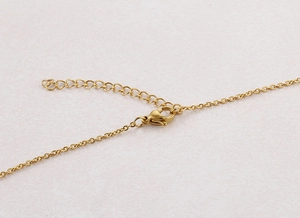 Close-up of gold titanium steel necklace with lobster clasp and teardrop extension chain