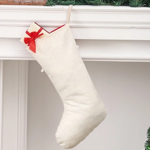 Détail d'une chaussette de Noël en lin crème avec un coffret cadeau sur une cheminée
