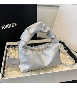 Close-up of silver pleated crescent bag with gold hardware and Fashion Bags tag