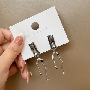 Macro shot of liquid metal earrings with irregular silver shapes and grey square crystals