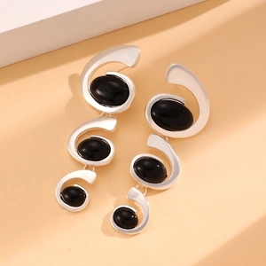 Detail view of silver spiral earrings with black oval stones in a modern artistic style