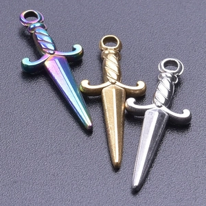 Macro shot of three sword-shaped stainless steel DIY jewelry pendants in various finishes