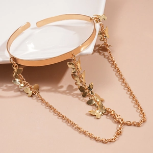 Close-up of golden butterfly tassel cuff with dangling chains on a white plate
