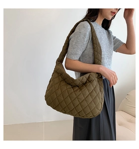 Dettaglio borsa hobo trapuntata oliva con spessa tracolla imbottita su una modella