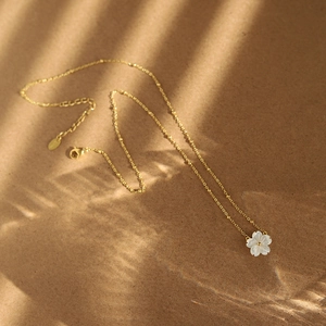 Macro detail of 18K gold plated necklace with delicate white shell flower pendant