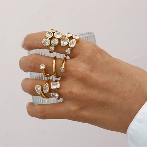 Three-piece gold-plated zircon rings set on hand holding a textured glass cup