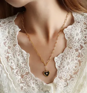 Detail of a 18K gold plated heart necklace with black inlay and a small gemstone