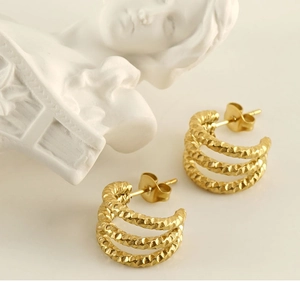 Detailed view of gold woven texture U-shaped stainless steel earrings on white background
