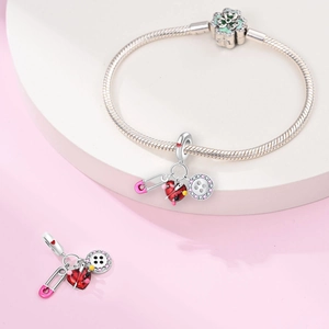Silver snake chain bracelet with pink safety pin, red heart and button charms