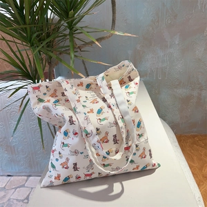 Detailed view of canvas tote bag featuring cute cartoon dog prints on cream cotton fabric