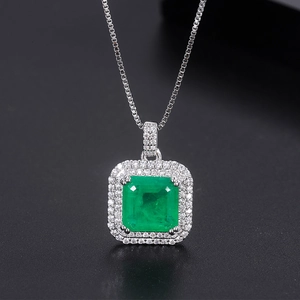 Vue macro d'un collier avec pendentif émeraude carré et petits diamants sur fond noir