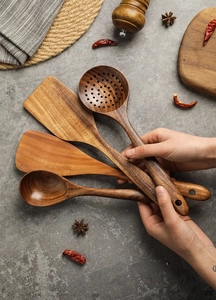 Three-piece solid teak wood kitchen utensil set including spatula and ladle on countertop