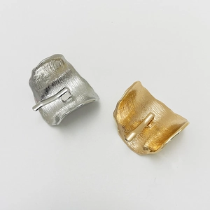 Detail of wavy textured alloy hair clips in gold and silver finishes on white background