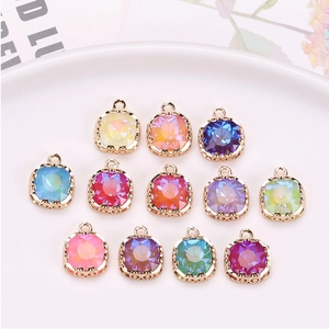 Close-up of colorful square crystal charms with gold edges arranged on a white plate