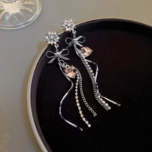 Detail of silver long tassel earrings with pink heart crystals and rhinestone bow accents