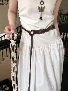 Detail of hand-woven retro waist belt with acrylic beads and circular buckle on white dress