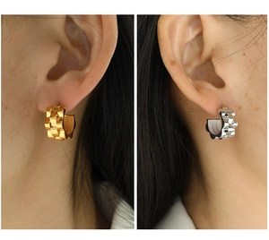 Detailed view of gold and silver chain texture hoop earrings worn on a model