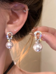 Detail of silver horseshoe earrings with zircon diamonds and elegant white round pearls