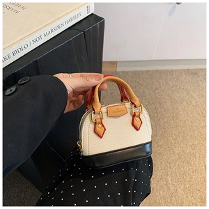 Gros plan d'un mini sac bicolore avec texture litchi et détails de bordure rouges