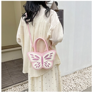 Detail of a pink butterfly-shaped crossbody bag with sequins worn by a model