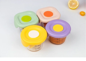 Close-up of four 200ml glass baby food jars with colorful silicone lids and volume markings