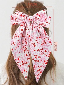 Detail of a large white bow hair clip with red heart prints and 17x30cm long ribbons