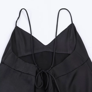 Detail of black satin camisole top showing the thin straps and cross back lace-up design