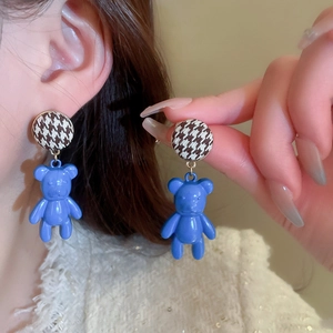 Detailed view of blue bear stud earrings with brown houndstooth pattern and resin finish
