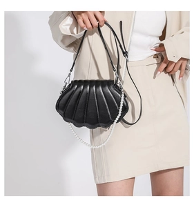 Detail der schwarzen muschelförmigen Handtasche mit Perlenkette und Muschelstruktur