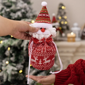 Knitted Christmas gift bag with Santa Claus head and snowflake patterns held by hands